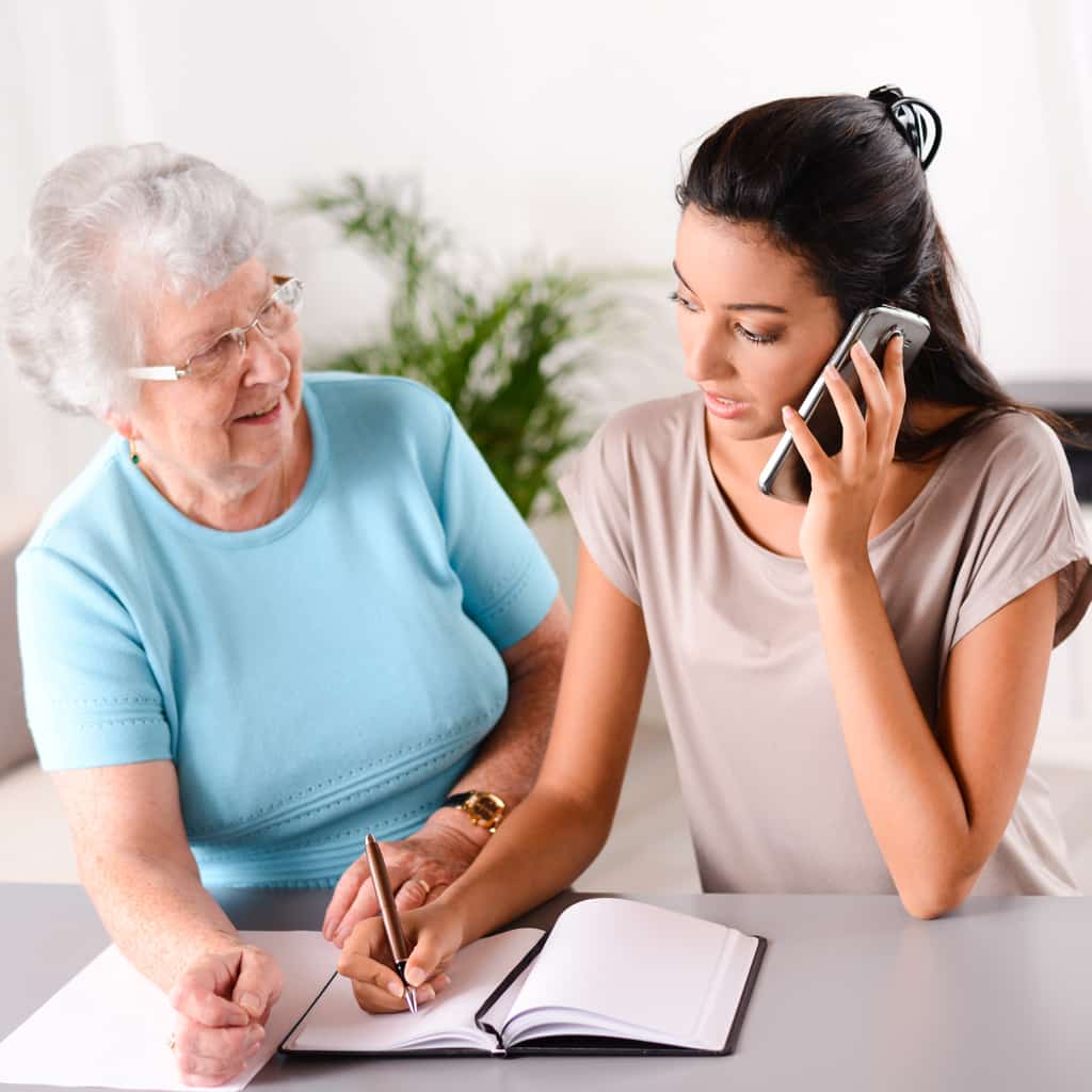 Cuidador por teléfono Cuidador hablando por teléfono con el amor de los ancianos uno mirando.